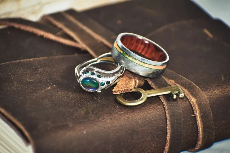 Dua cincin perak dengan batu hijau di atas sampul kulit