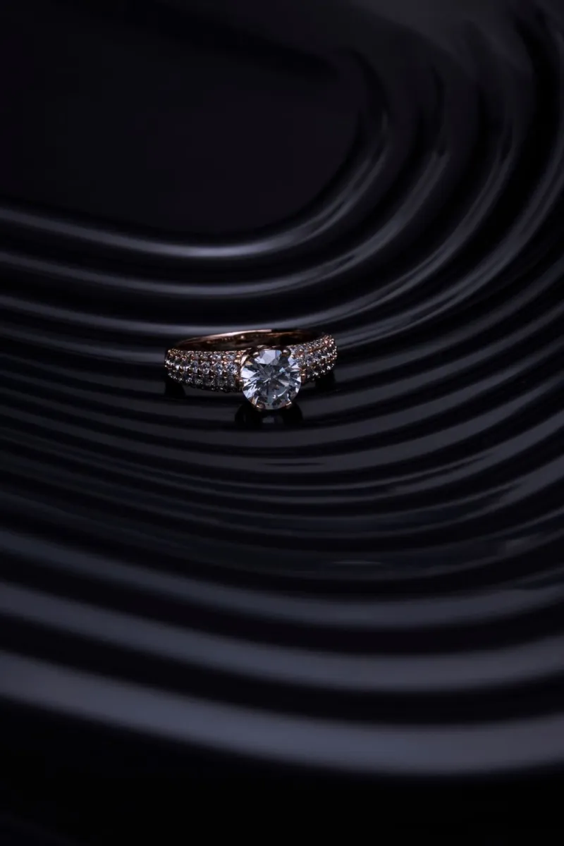 Cincin solitaire dengan batu bening di atas latar gelap